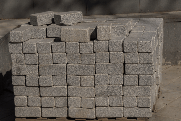 Stack of gray granite paving stones neatly stacked on a wooden pallet