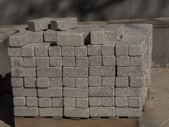 Stack of gray granite paving stones neatly stacked on a wooden pallet