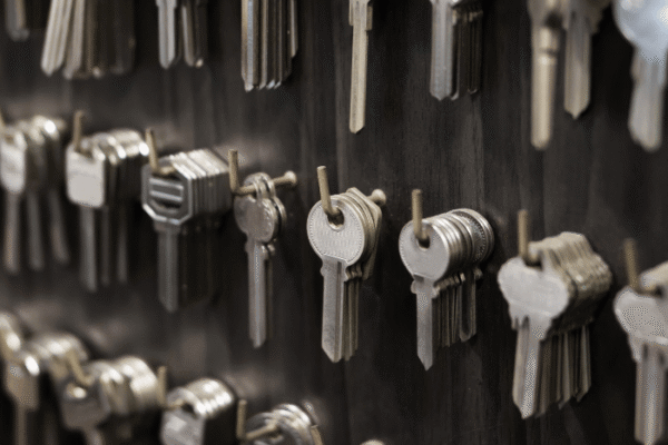 Rows of metal keys hanging on hooks against a dark wall, organized in clusters