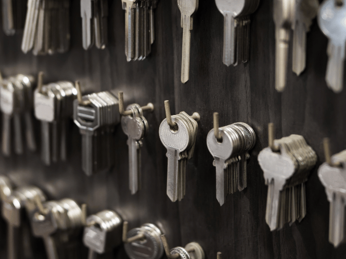 Rows of metal keys hanging on hooks against a dark wall, organized in clusters