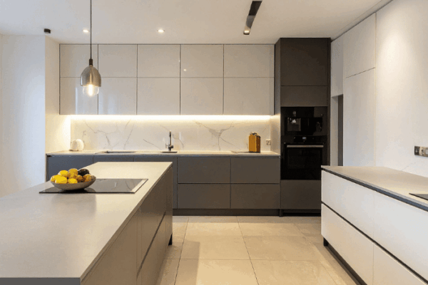 Modern gray kitchen with an island, marble backsplash, pendant light, and a bowl of lemons on the island.